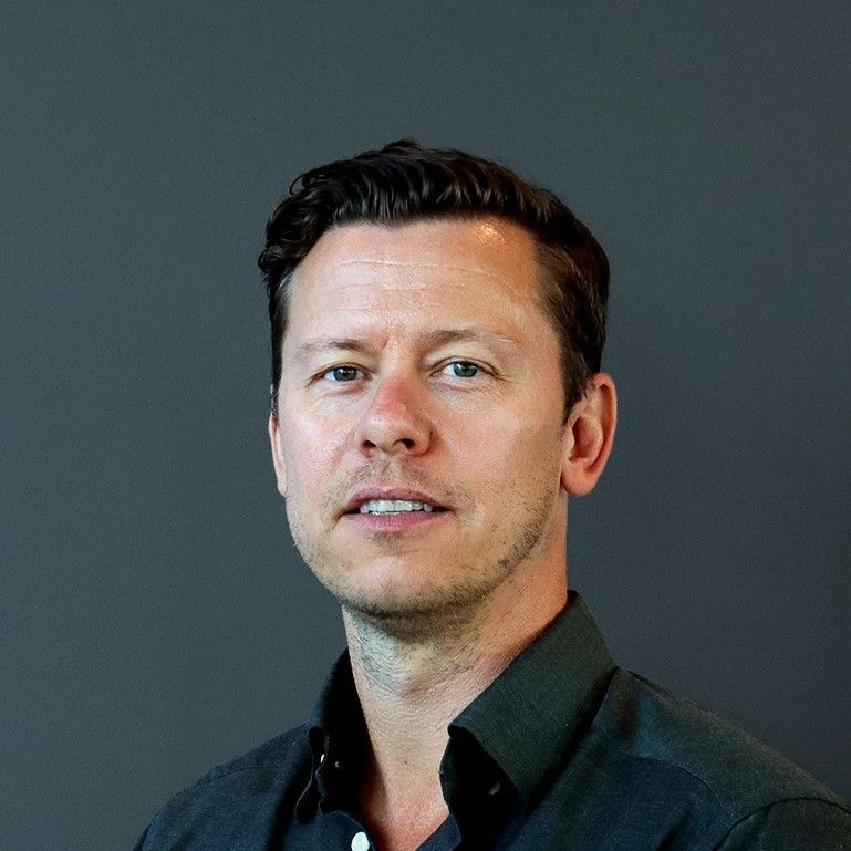 Stefan Helgesson, advisor, in a dark shirt photographed against a plain slate-gray background